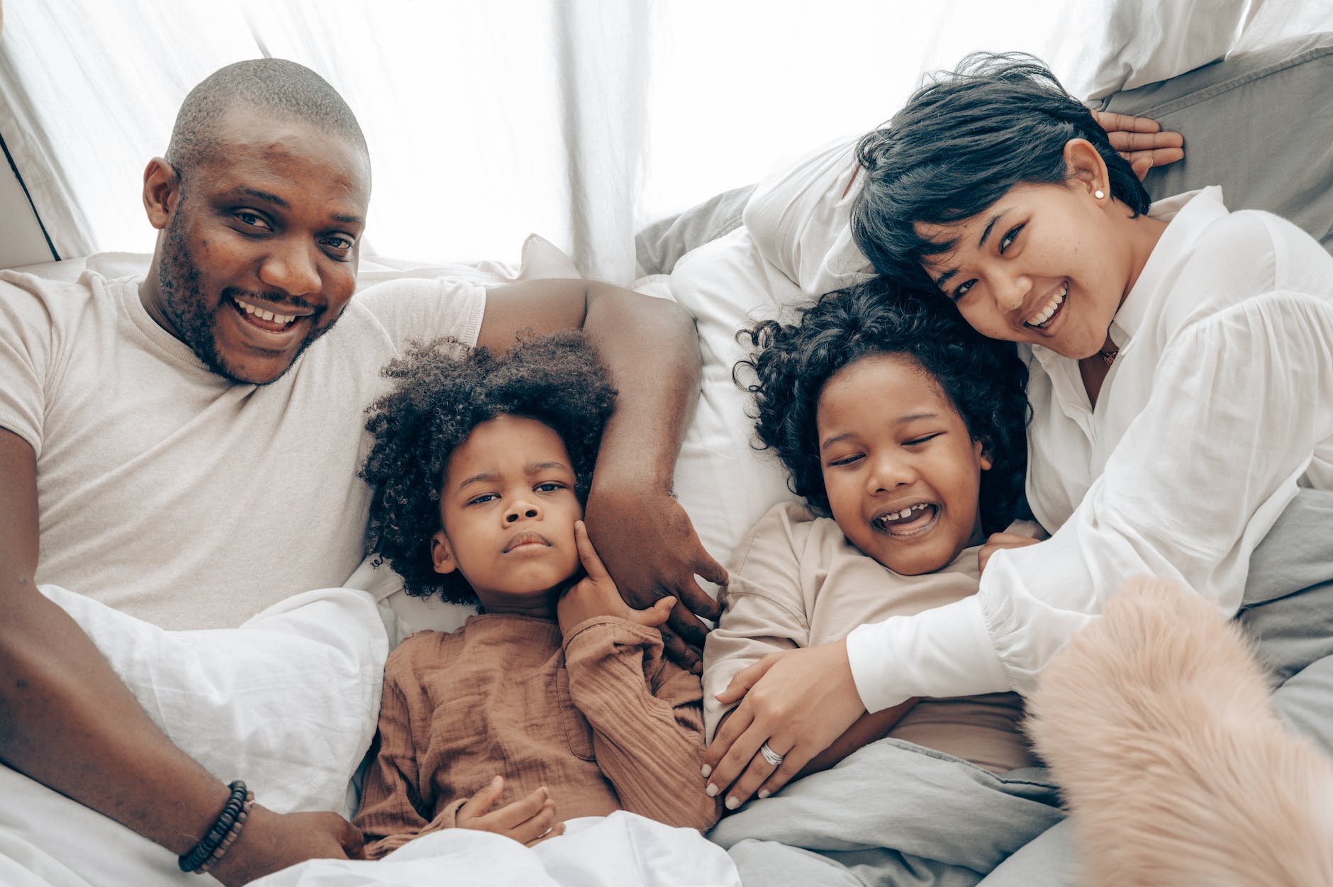 happy diverse family resting on bed in morning